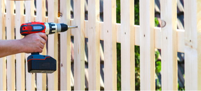 hand screwing wooden fence with cordless drill