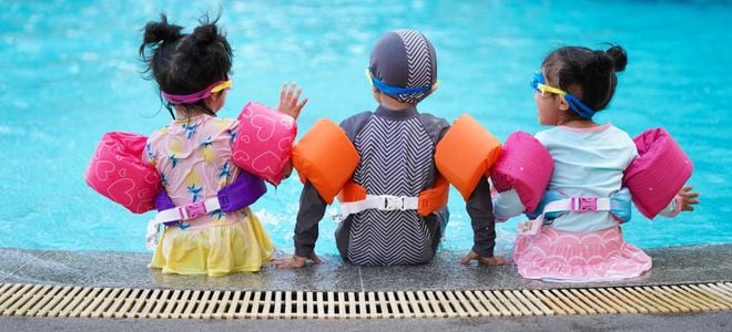 Kids sit by the side of a pool