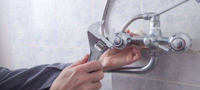 hand with wrench adjusting shower handle