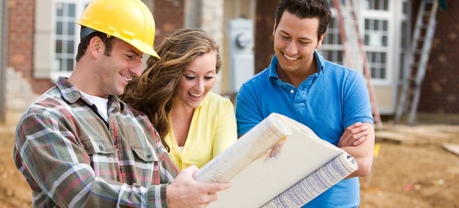smiling couple looking at home plans with a contractor