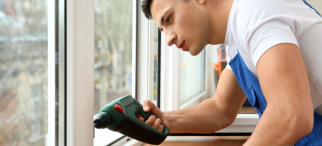 man fixing sliding window with a drill