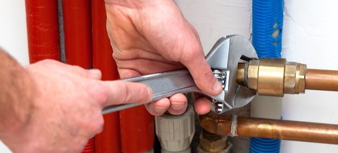 hands with a wrench adjusting a pipe