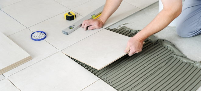hands installing bathroom tile floor