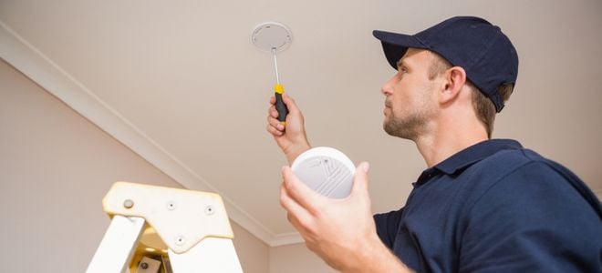 worker installing carbon monoxide detector