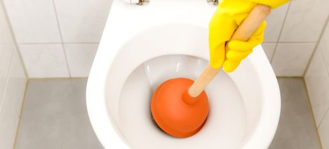 gloved hands plunging toilet