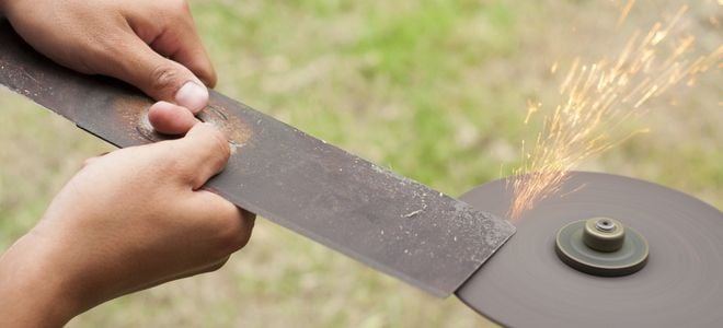hands sharpening lawnmower blade