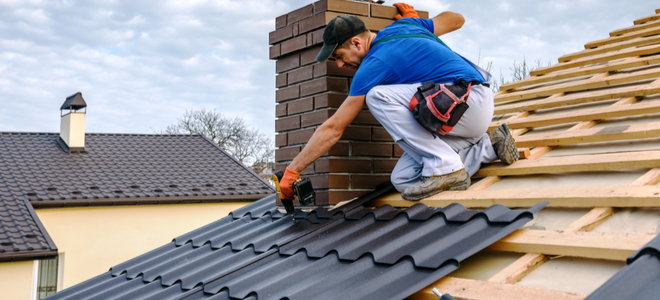 man installing metal roofing panels