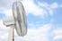 A standing fan against a partly cloudy blue sky.