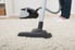 A vacuum cleaner being used to vacuum a carpet.
