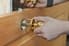 A pair of hands installing a doorknob on a door. 