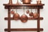 Copper pots and pans hanging from a wall rack.