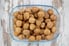 A glass tray of walnuts on a rustic wood background. 