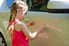 A little girl scratches a car.