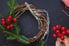 a grapevine wreath with evergreen and holly berries