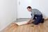 man rolling out linoleum flooring