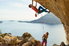 man and woman rock climbing with ropes in a beatiful coastal area