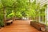 A backyard wood deck surrounded by bright green trees.