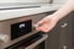 person turning knob to change temperature on stainless-steel electric oven