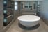 A white oval shaped bath tub in an expensive new home in an ultra modern bathroom.