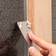 A putty knife is used to scrape excess putty from a window.