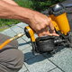 Carpenter uses nail gun on a roofing job.
