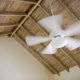 a wooden ceiling peak with white ceiling fan in motion