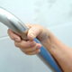 senior citizen hand holding a grab bar installed on tile wall