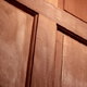 A raised-panel, interior door made with mahogany wood.