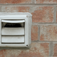 dryer vent outside mounted to a brick wall