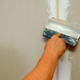 A hand applying drywall.