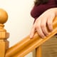 A hand sits on a finished wooden banister.