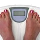 A person weighing themselves on a digital scale.