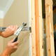 man using pry bar to remove drywall from the interior stud framing