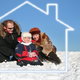 A family sits outside on the snow surrounded by the outline of a house.
