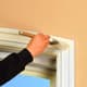 A person painting window trim with white paint.