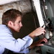 A man working with a wrench on a gas furnace.
