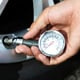 hand checking tire pressure with a gauge