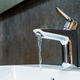 A stainless steel bathroom faucet with water running from it.