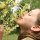 girl smelling flowers on a honeysuckle vine