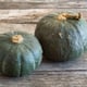 Two winter squash sitting on a wood surface.