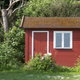 A small, red, wooden shed tucked away in a back yard.