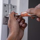 hands with screwdriver adjusting door hinges