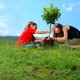 Two young girls planting a tree.