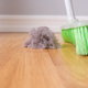A broom sweeping up a dust bunny that's an indoor air pollutant.