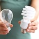 person holding two types of light bulbs