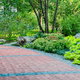 red paver walkway on a slight slope surrounded by greenery