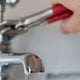 hand with wrench working on sink faucet plumbing