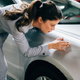 an upset woman inspects a scratch on her car in a parking garage