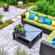 a stone patio with couches, plants and a table