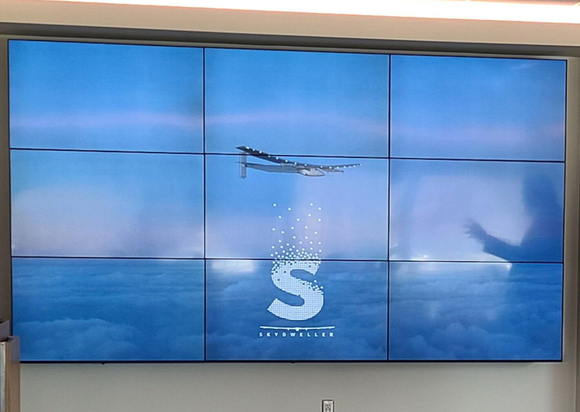 Large screen shows the logo for the U.S. Navy's Skydweller solar-powered aircraft.